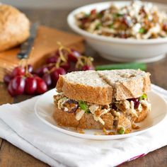 a sandwich on a plate with grapes and bread in the background