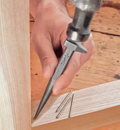 a person holding a drill and screwdriver in their hand while working on a piece of wood