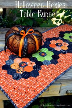 an orange pumpkin sitting on top of a table next to a black and white quilt