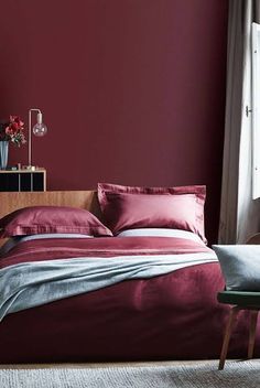 a bed with red sheets and pillows in a bedroom