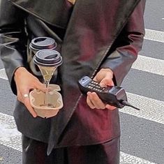 a man in a leather jacket holding a cell phone and some sort of cup holder