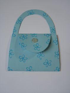 a blue purse with flowers on it sitting on top of a white table next to a wall