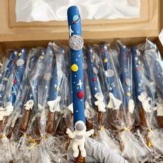 a box filled with space themed candles in plastic wrappers and some kind of stick sticking out of it's side