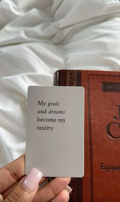 a person holding up a card that says, my goals and dreams become my reality