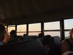 people are sitting on a bus looking out the window at windmills in the distance