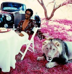 a man sitting in front of a table next to a lion