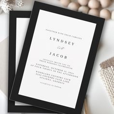 two black and white wedding cards sitting next to each other on top of a table