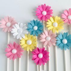 colorful paper flowers are on top of white sticks