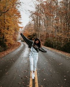 a woman standing on the road with her arms in the air