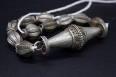 Antique, authentic and used necklace with metal beads from South Nepal, Terai Area. These Necklaces have been used by the Tribal Village Women ( Rana Tharu Tribe) as adornment. Ten antiques matched tribal silver (silver alloy) beads of collared shape and a traditional tribal silver pendant of biconical shape. Collectible and useful as jewelry supplies. Average beads measures/wt: 21 x 12 mm/9.6g Pendant measures/wt: 66.3 x 23.2 mm/28.1g Total Weight: 124 grams. Origin: Nepal Vintage Ceremonial Jewelry With Polished Beads, Vintage Silver Beaded Necklaces For Festivals, Antique Silver Beads Jewelry For Festivals, Antique Silver Beaded Jewelry With Round Beads, Vintage Silver Beaded Necklaces For Festive Occasions, Vintage Silver Beaded Necklace For Festive Occasions, Vintage Silver Beads Necklace For Festivals, Traditional Silver Beads For Festivals, Handmade Silver Beaded Necklace For Ceremonial Use