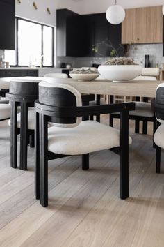 a dining room table with four chairs and a bowl on the table in front of it