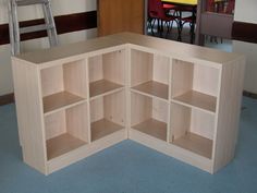 a corner shelf with several open shelves on the floor and chairs in the back ground