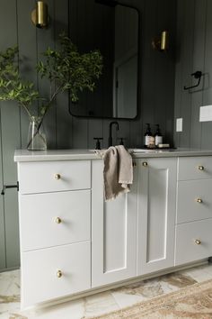 a bathroom with white cabinets and a plant in a vase on the sink counter top