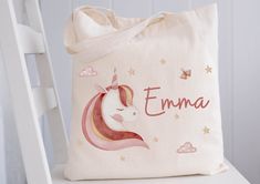 a pink unicorn tote bag sitting on top of a white chair