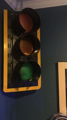 a traffic light hanging from the side of a blue wall next to a framed photograph