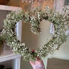 a heart - shaped wreath with baby's breath hanging from the ceiling in front of a mirror