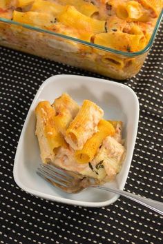 a casserole dish with pasta and chicken in it next to a glass baking dish