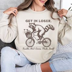 Everyone loves the funny raccoon & opossum meme trend so of course we combined it with the popular "get in loser" trend and put it on a sweatshirt. This shirt is sure to get some giggles, and who doesn't need some laughs these days? The perfectly distressed graphic is printed on our cozy fleece sweaters made for staying comfy while your lounging, working, or running errands. Find more fun & trendy designs at https://bellawarriorboutique.etsy.com 💌Enjoy FREE SHIPPING IN THE U.S. ON ORDERS OF $35 Raccoon Gift, Get In Loser, Funny Raccoon, Lover Sweatshirt, Raccoon Funny, Embroidered Crewneck, Embroidered Clothes, Fleece Sweater, Trending Today