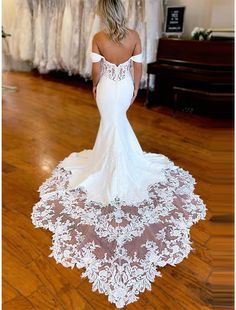 a woman in a white wedding dress standing on a wooden floor with her back to the camera