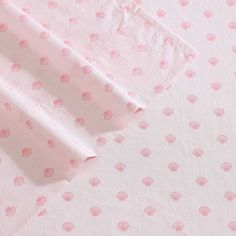 pink and white polka dot fabric on top of a bed sheet with two sheets folded over it