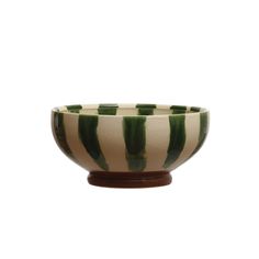 a green and white striped bowl sitting on top of a wooden stand