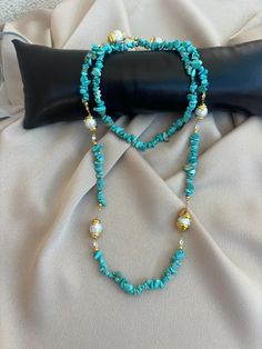 a blue beaded necklace sitting on top of a black pillow