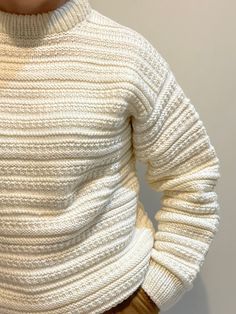 a woman wearing a white turtle neck sweater and brown pants with her hands on her hips