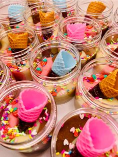 small glass jars filled with different colored ice creams and desserts on top of a table