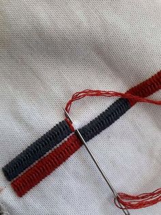 a red, white and blue striped piece of fabric being sewn