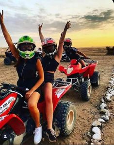 three people are riding four wheelers in the desert at sunset or sunrise with their hands up