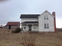 an old white house sitting on top of a dry grass field