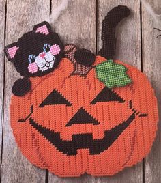 an orange knitted pumpkin with a black cat on it