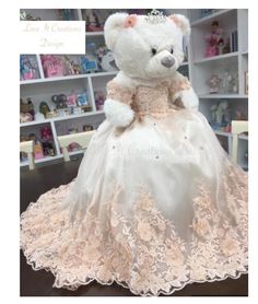 a white teddy bear dressed in a wedding dress with pink lace on the skirt and headband