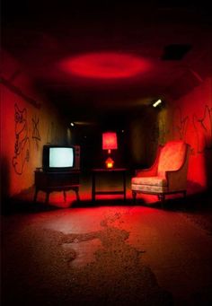 two chairs and a television in a dark room with red light coming from the ceiling