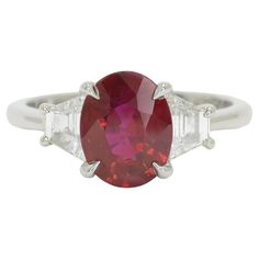 The Beaumont natural ruby engagement ring is centered by a vivid, pigeon blood red oval ruby certified by the Gemological Institute of America. A classic, 3 stone platinum mount featuring elegant claw prongs is accented by a pair of dazzling trapezoid shape diamonds and sits low on your hand for everyday enjoyment. This amazing gemstone bridal design is quite captivating given the glowing, fiery color of this modern treasure.   Condition: New Era: Classical Year: 2021 Metal: Platinum Center Gems Luxury Oval Three-stone Ruby Ring, Luxury Three Stone Ruby Ring, Classic Red Three Stone Rings, Oval Ruby Ring With Three Diamonds, Oval Three Stone Ruby Ring With Diamonds, Formal Red Ruby Ring With Three Stones, Formal Ruby Three Stone Ring, Formal Red Three Stone Ruby Ring, Classic Red Three-stone Ring