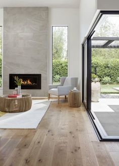 a modern living room with wood floors and white walls, along with large windows that look out onto the backyard