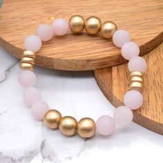 Dreamy rose quartz and golden wood beads make up our newest gemstone bracelet! The gorgeous pale pink rose quartz gemstones in this bracelet are matte and perfectly contrast the super shiny golden wood beads in this design. Rose Quartz is said to be a fantastic stone to wear for promoting self-love, fostering positive relationships, and attracting love and compassion. Get this bracelet for yourself or for a friend and adorn yourself with Dreamy Rose Quartz! Rose Quartz is a form of quartz that i Spiritual Gold Beaded Rose Quartz Bracelets, Gold Rose Quartz Beaded Bracelets, Gold Rose Quartz Beaded Bracelets With Round Beads, Gold Beaded Bracelet With Rose Quartz Round Beads, Gold Beaded Bracelets With Rose Quartz Round Beads, Gold Beaded Bracelets With Rose Quartz, Internal Healing, Loved And Lost, Attracting Love