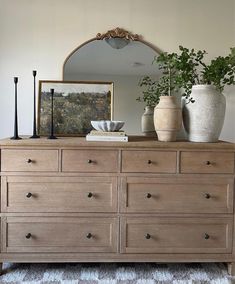 a dresser with two vases on top and a mirror above it in a living room