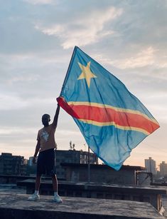 a man holding a flag on top of a roof