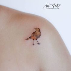 a small bird tattoo on the back of a woman's left shoulder and breast