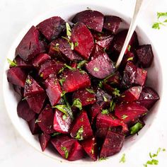 a white bowl filled with cooked beets and parsley