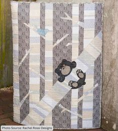 a teddy bear quilt hanging on the side of a building