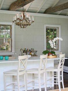 a bar with four stools in front of it and a chandelier hanging from the ceiling