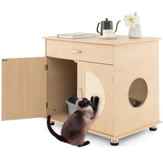 a cat sitting in the corner of a wooden cabinet next to a white flower vase