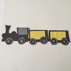 a paper cut out of a train on a white surface with black and yellow accents