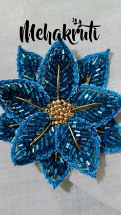 the brooch is made with blue thread and gold metal beads, which are attached to a white shirt