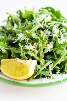 a salad with lemon wedges and parmesan cheese on the top is ready to be eaten