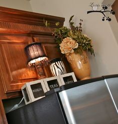 a vase with flowers sitting on top of a metal refrigerator next to a clock and other items