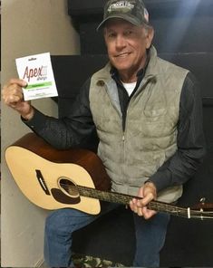 an older man is holding up a guitar