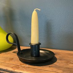 a candle is sitting on top of a black plate next to a yellow vase and banana